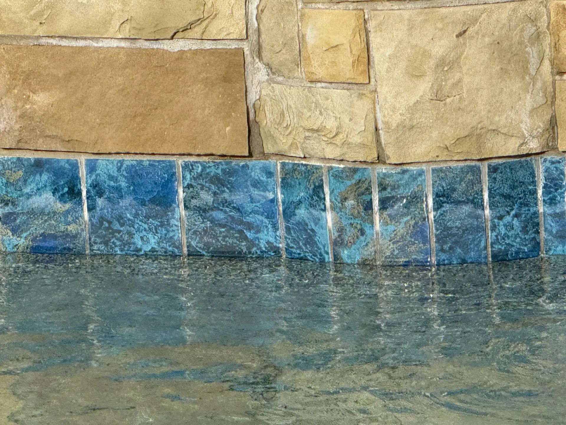 Blue pool waterline tile below stone coping